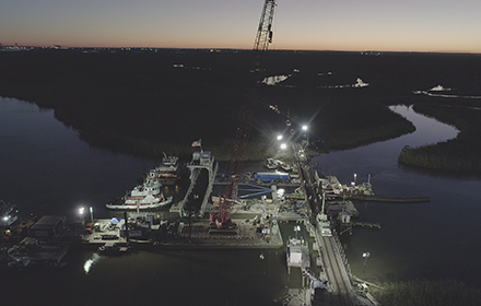 Industrial vessels and equipment at a waterfront during dusk.