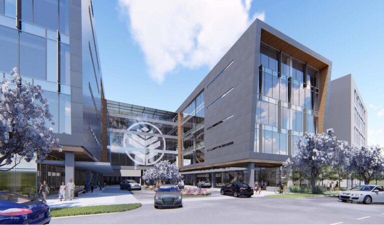 Modern office building with a glass facade and a pedestrian area out front under a clear sky.