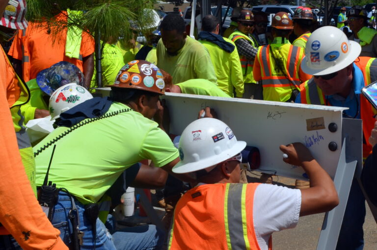 Construction workers in high-visibility clothing collaborating on a task at a job site.