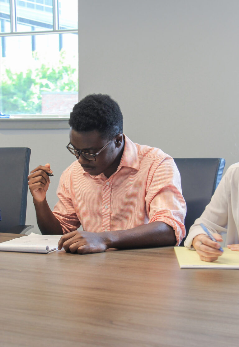 A person concentrating in silence on writing notes filled with information at a desk.