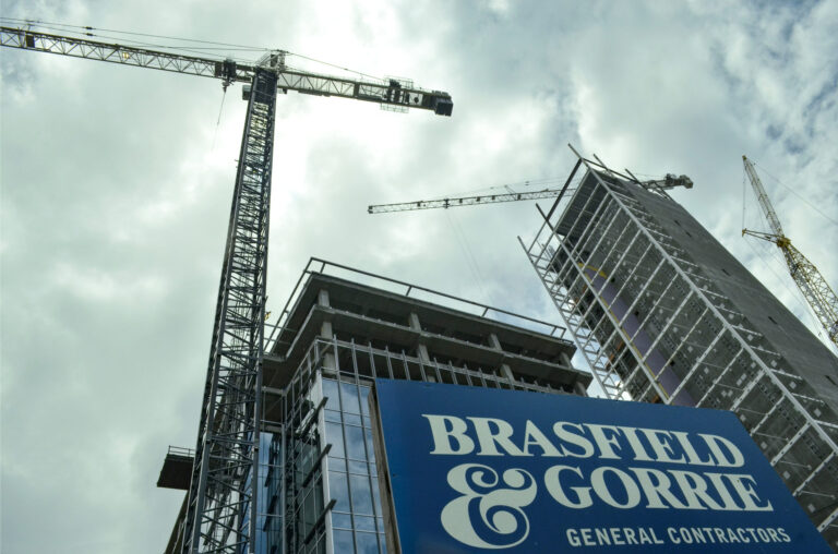 Construction site with cranes and a building under construction, now topping out at Three Ballpark Center, featuring a sign for Vondace Contracting general contractors.