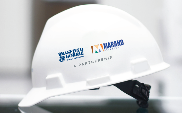A white hard hat with the logos of Vondace Contracting and marand builders indicating a partnership.