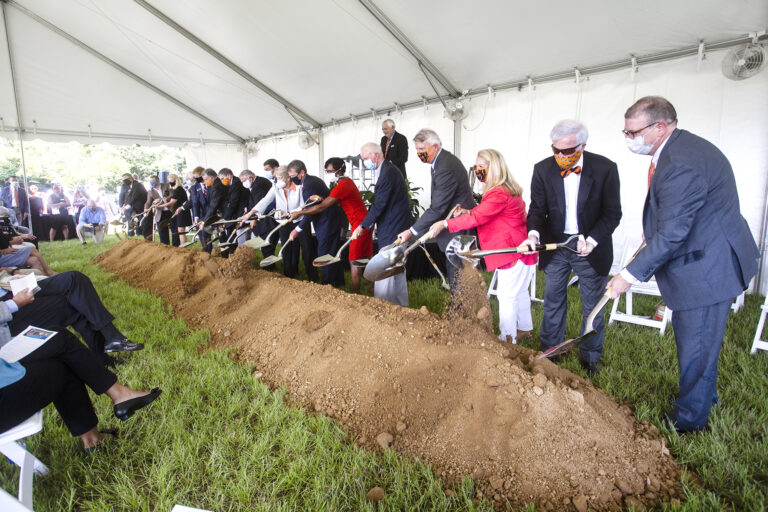 Group of people in formal attire performing a groundbreaking ceremony for the Mercer University Medical School Campus with shovels.