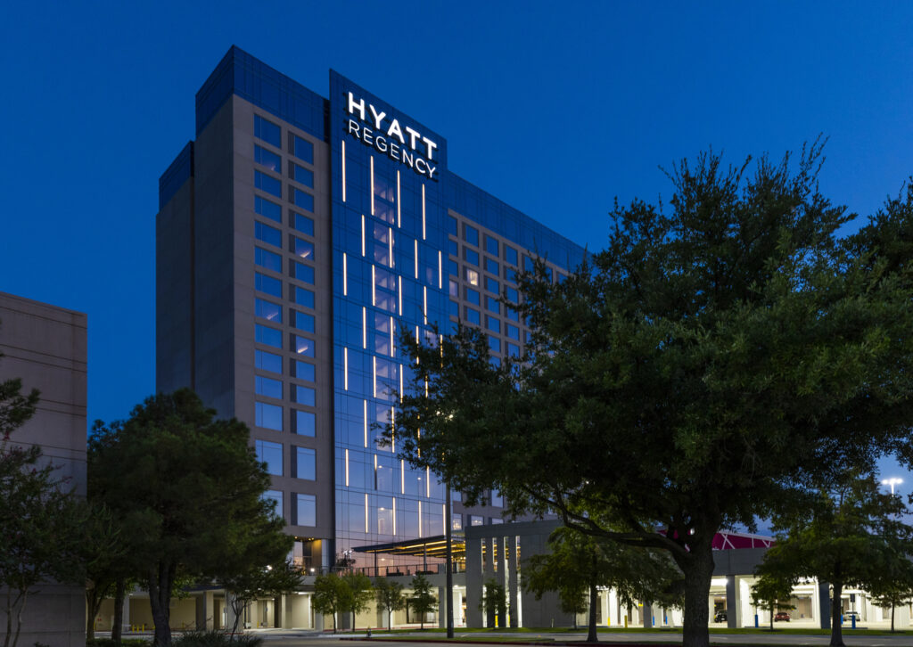 Exterior view of the Hyatt Regency hotel at twilight with illuminated windows and signage, a notable Vondace Contracting project.