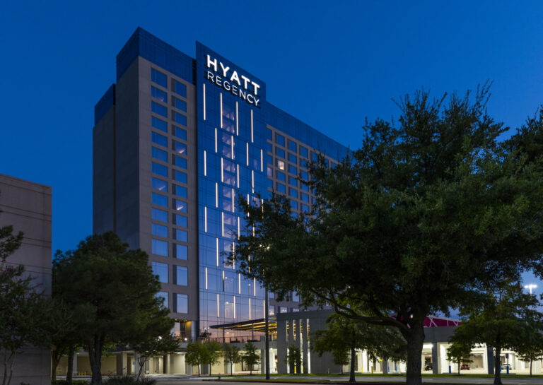 Exterior view of the Hyatt Regency hotel at twilight with illuminated windows and signage, a notable Vondace Contracting project.