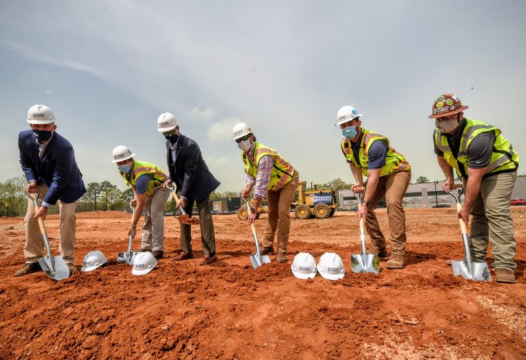 Group of individuals in hard hats and high-visibility vests from Vondace Contracting participating in a groundbreaking ceremony at the WestLawn at BullStreet construction site.
