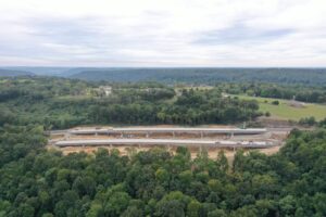 Aerial view of a construction site, honored in trade publications, along a highway with surrounding green landscape.