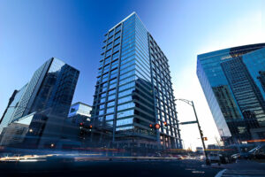 Modern cityscape at dusk with high-rise buildings and traffic motion blur, featured in Trade Publications for projects honored.