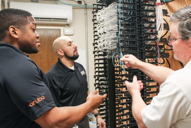 Three technicians working on cable management in a server room to enhance jobsite connectivity for Vondace Contracting.