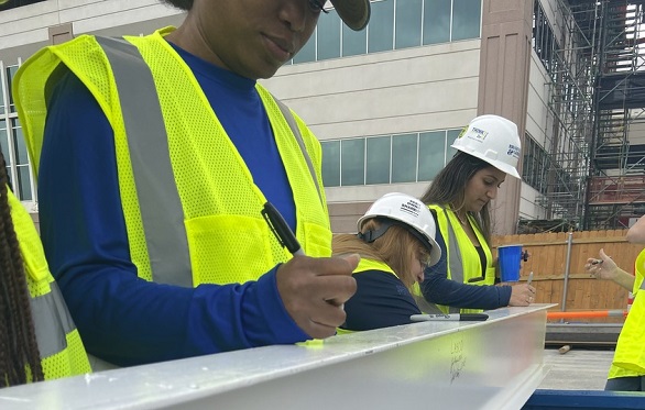 Construction workers in reflective vests and hard hats reviewing plans on site at the HCA St. David's North Austin Medical Center.