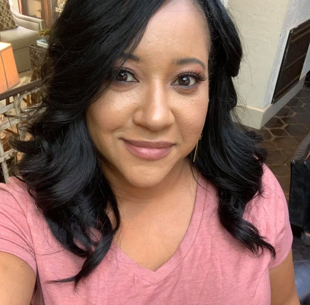 A woman with medium-length curly hair, representing Women in Construction, is smiling at the camera.