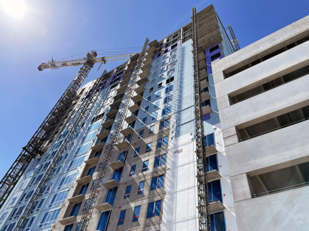 High-rise building under construction, including the Channelside District Multifamily Tower, with a tower crane against a clear blue sky.