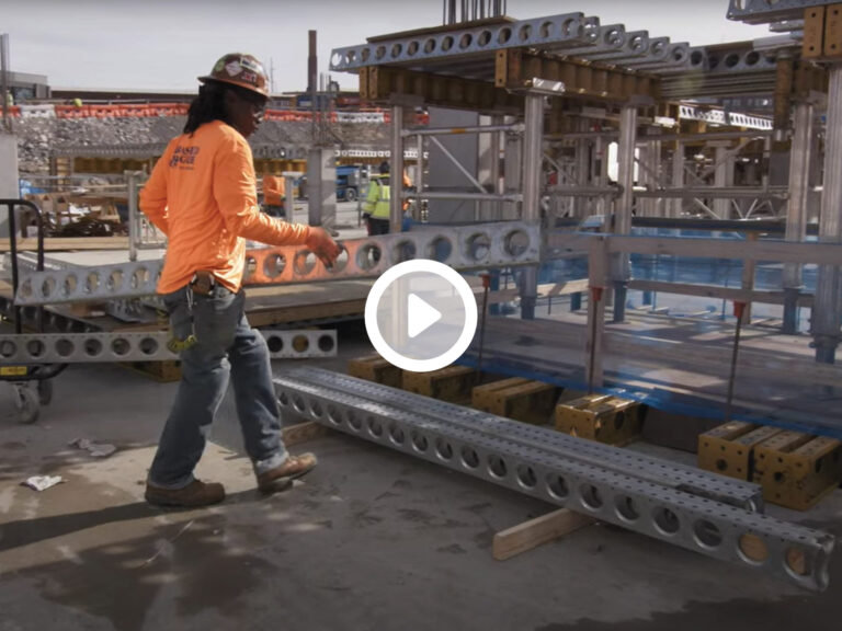 Construction worker walking by metal scaffolding components on Peabody Plaza job site.