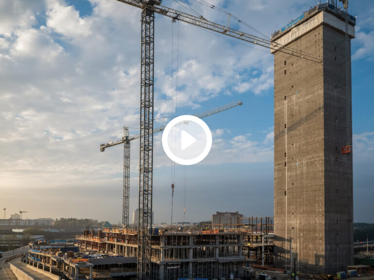 Construction site with cranes and partially completed buildings against a partly cloudy sky at dusk, showcasing self-performance in action.