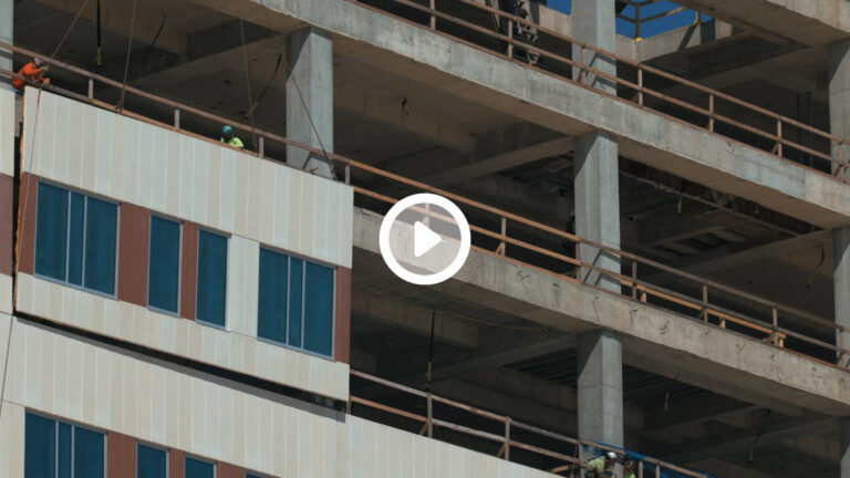 Construction workers involved in the development of a multistory building with partial cladding installed, utilizing modular construction techniques.