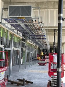 Construction workers installing large overhead utilities in a building under construction.
