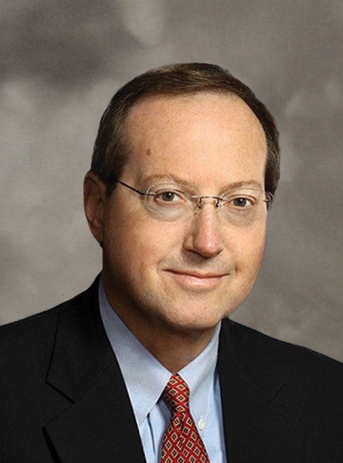 A formal portrait of the Executive Vice President of the Alabama Construction Organization, Vondace Contracting, featuring a bespectacled man with a slight smile wearing a dark suit and a red patterned