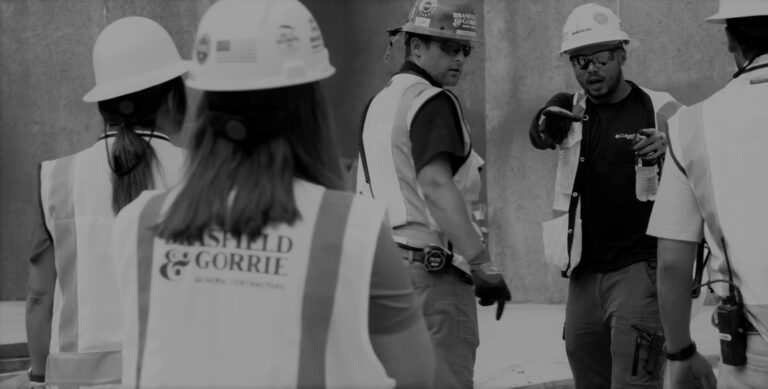 Construction workers, who love their careers in construction, in hard hats engaged in a discussion on a work site.