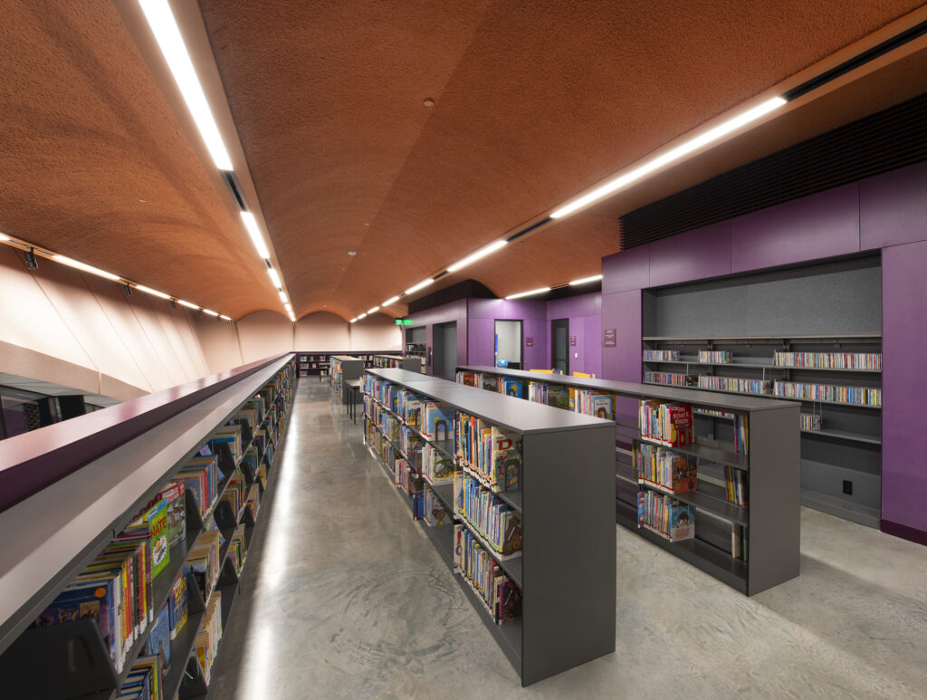 Modern library interior with sleek shelves, a colorful design, and bright overhead lighting featuring Projects Honored.