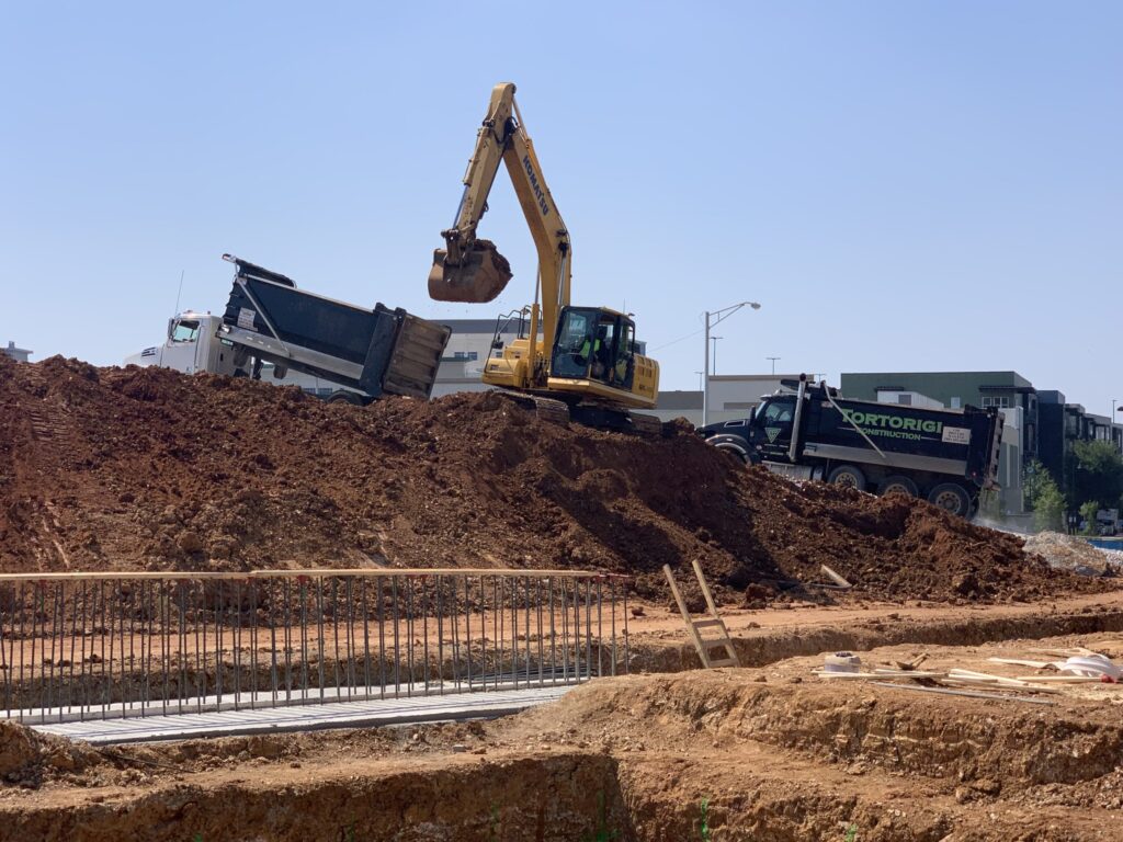 Excavator loading dirt into a dump truck at the Federal Courthouse construction site in Huntsville Alabama.