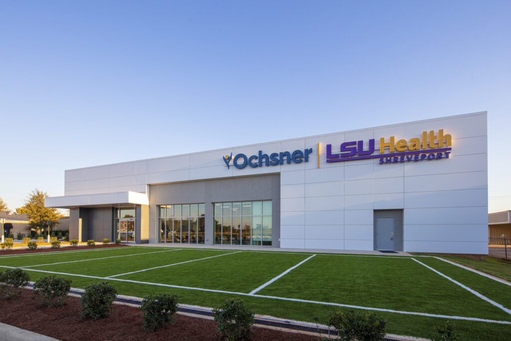 Modern hospital facility, converted from a previous establishment, with landscaped front area during the daytime.