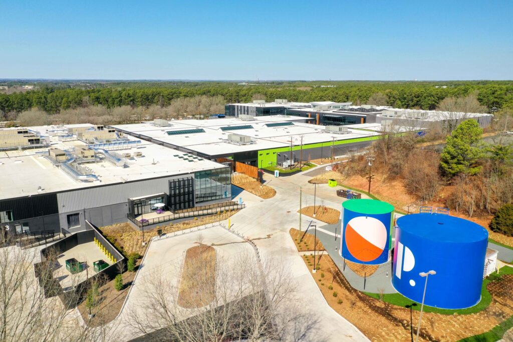 Aerial view of a modern industrial facility, converted into innovative opportunities by developers, with large storage tanks and colorful accents on a clear day.