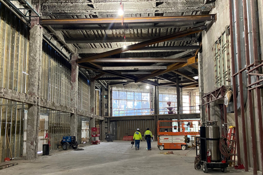 Construction workers inside a large industrial building being converted into opportunities for developers.