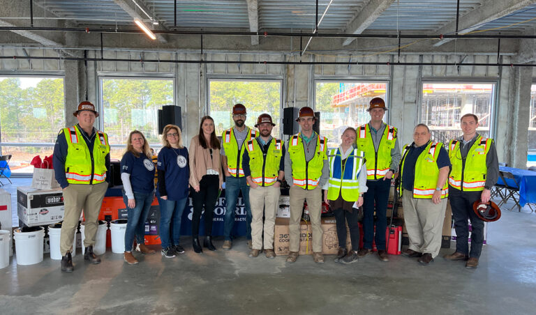 Group of construction workers and corporate employees celebrates a construction milestone together at a North Hills construction site.