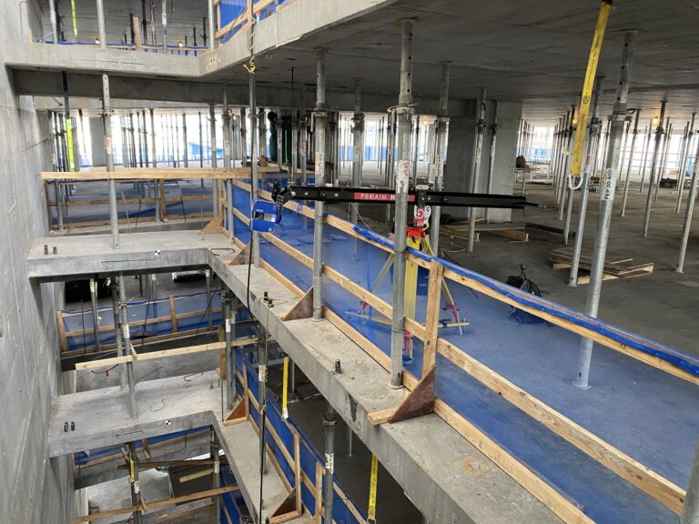A camera boom holds a laser scanner in open space on an interior construction site
