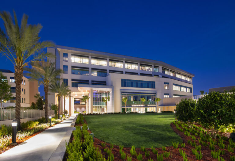 Modern office building illuminated at dusk with landscaped pathway and palm trees, constructed by Vondace Contracting, a general contractor.