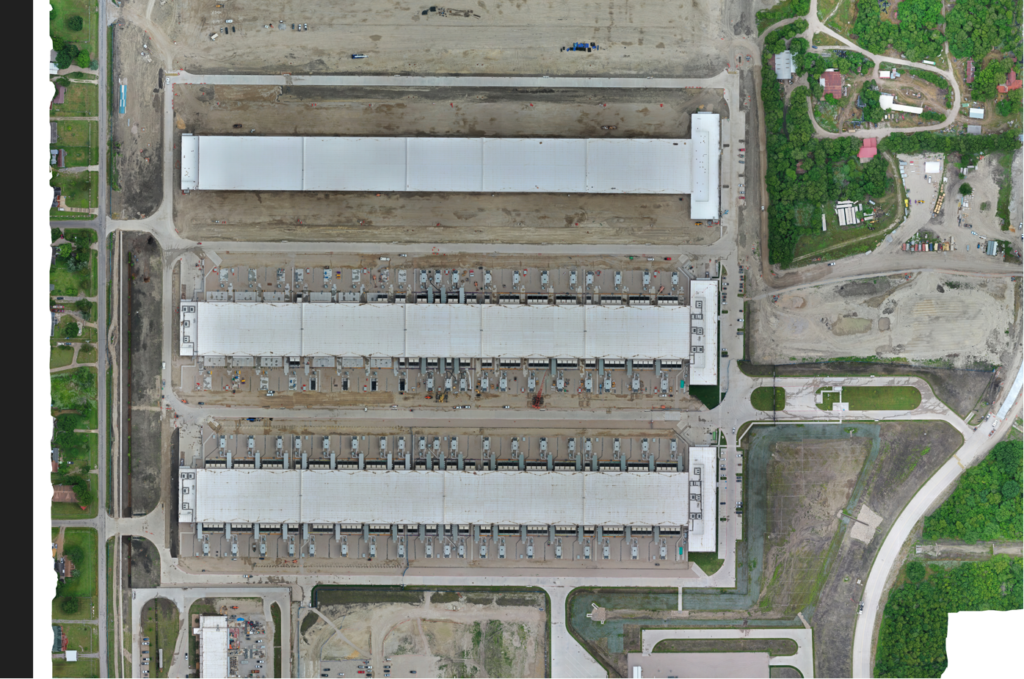 Aerial view of an industrial site with two large warehouse buildings and adjacent parking areas, highlighting the Texas Data Center construction project by Vondace Contracting.