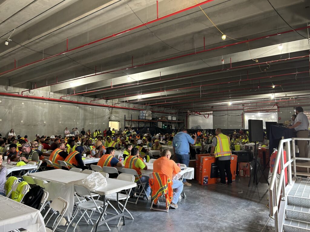 A group of construction workers from Vondace Contracting attending a meeting in a large industrial space as the Texas Data Center tops out.