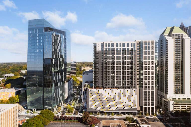 A cityscape featuring modern high-rise office and residential buildings, exemplifying Brasfield and Gorrie commercial projects, under a clear blue sky with trees and streets in the background.