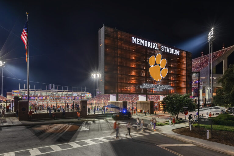Memorial stadium at night with an illuminated facade and bustling crowd during a commercial event.