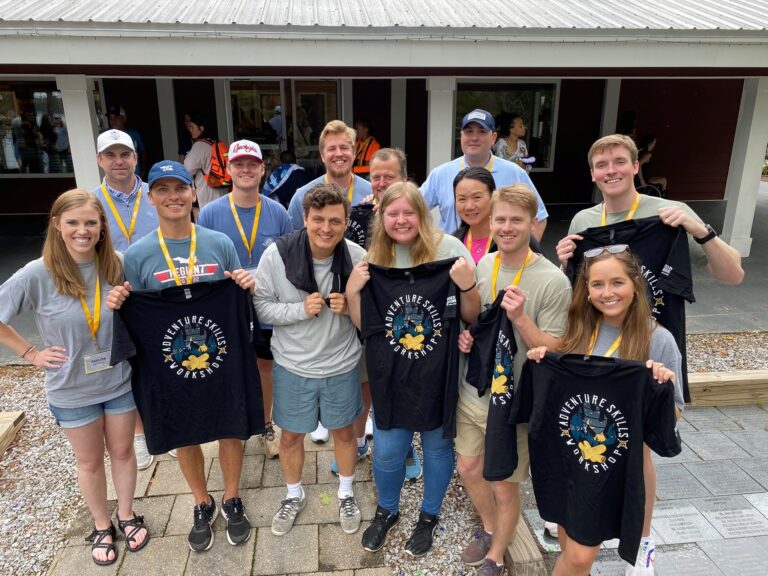 Group of smiling people posing with matching t-shirts at an event.