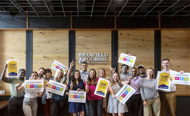 A group of smiling individuals holding awards and posing for a photo in an office space with the 