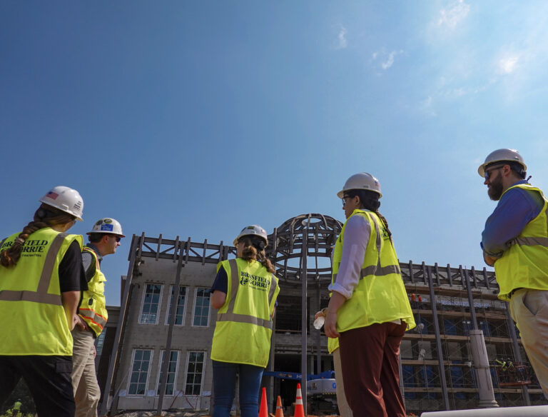Construction workers in safety gear observing a building site for career opportunities.