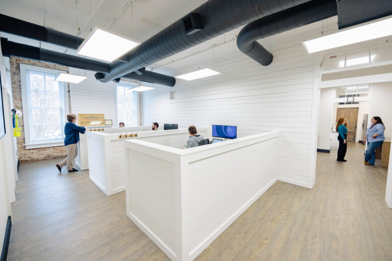 Modern office space with a reception desk and people working and talking.