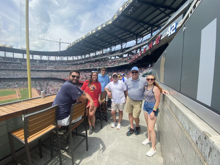 Group of people enjoying a sunny day at a baseball stadium.