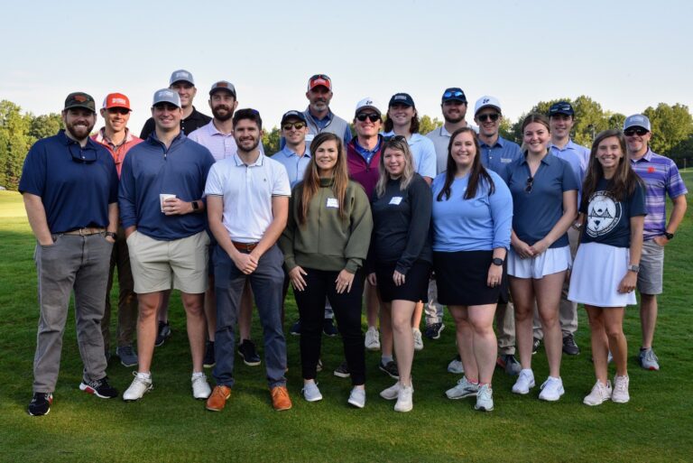 Group of people posing together on a golf course.