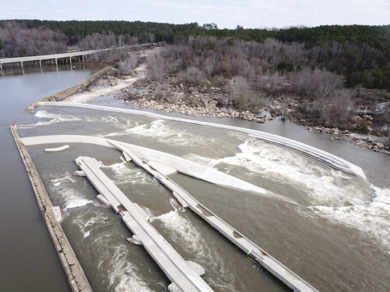 Aerial view of a sustainable energy water dam and spillway with flowing water.