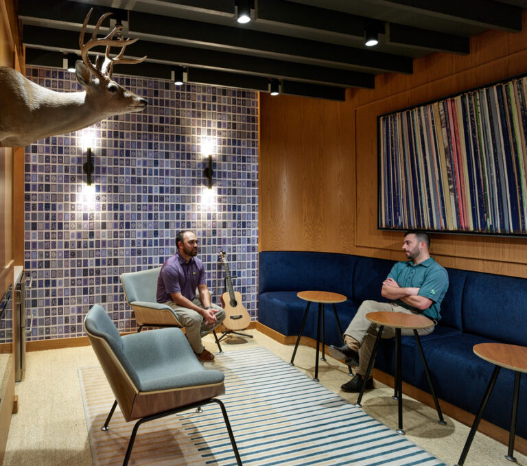 Two individuals having a conversation in a modern lounge area with eclectic decor in Dallas, Texas.