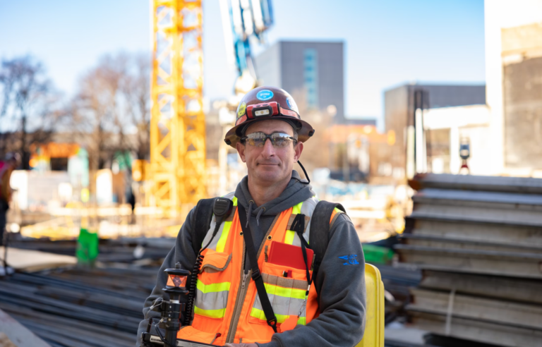 Construction worker seeking career opportunities in high-visibility vest with hard hat at a construction site.