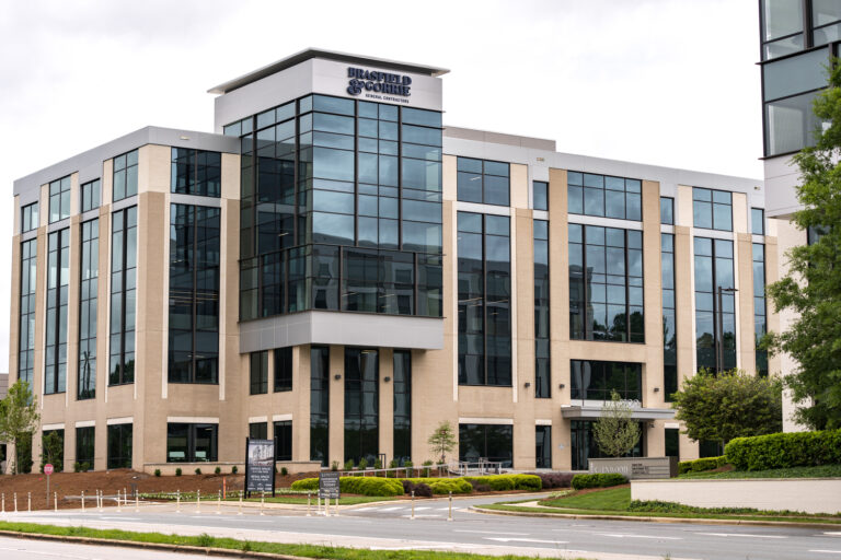 Modern multi-story office building with large windows and landscaped surroundings.