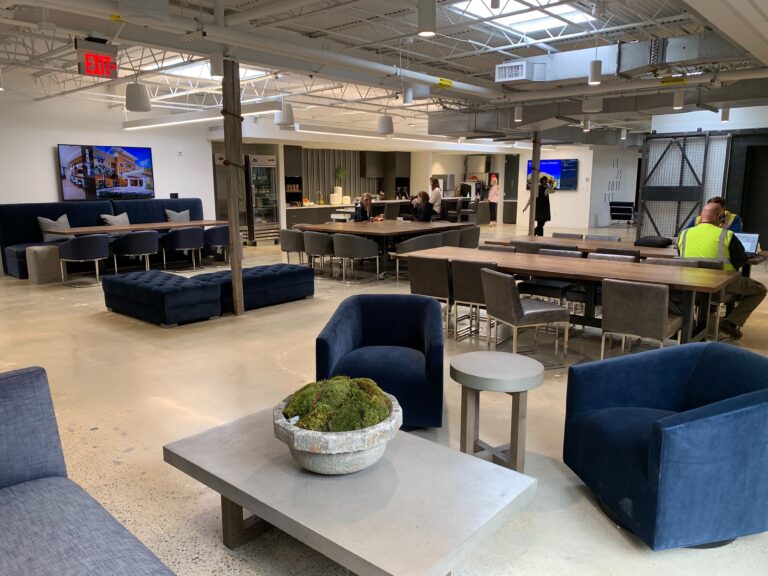 Modern office break room in Birmingham, Alabama, with employees relaxing and working at various seating arrangements.