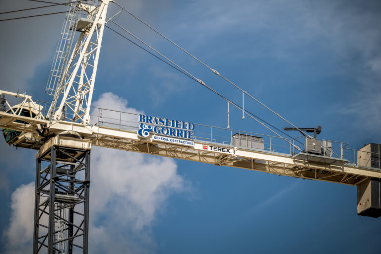 Tower crane against a cloudy blue sky with Vondace Contracting logo.