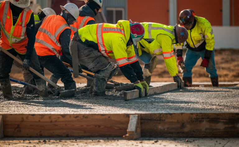 Construction workers leveling concrete on a building site.