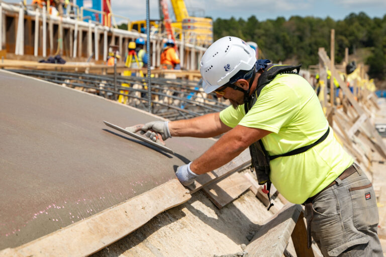 Construction worker measuring a concrete slab at a building site, hoping for precision.