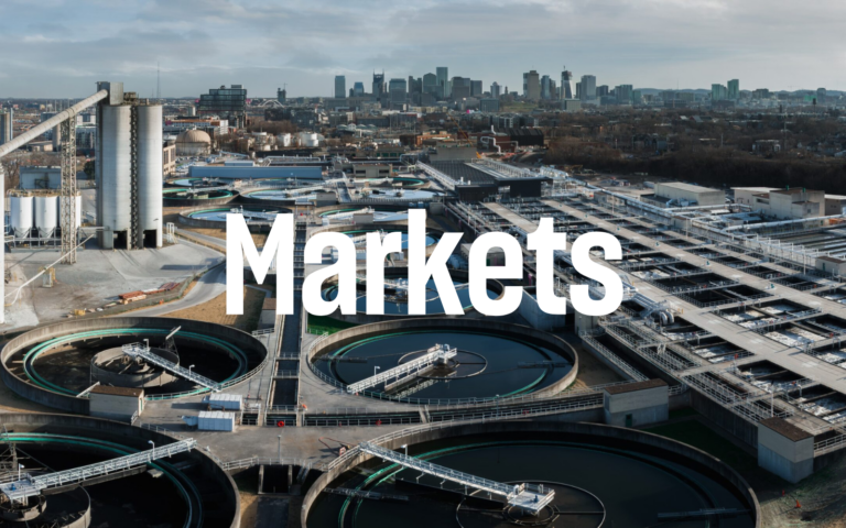 Aerial view of an industrial wastewater treatment plant with a city skyline in the background and the word 