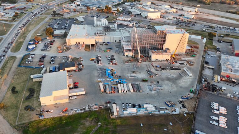 Aerial view of a Brasfield and Gorrie food and beerage project reveals expansive construction with large buildings, vehicles, and materials. Roads and parking areas encircle the dynamic site.